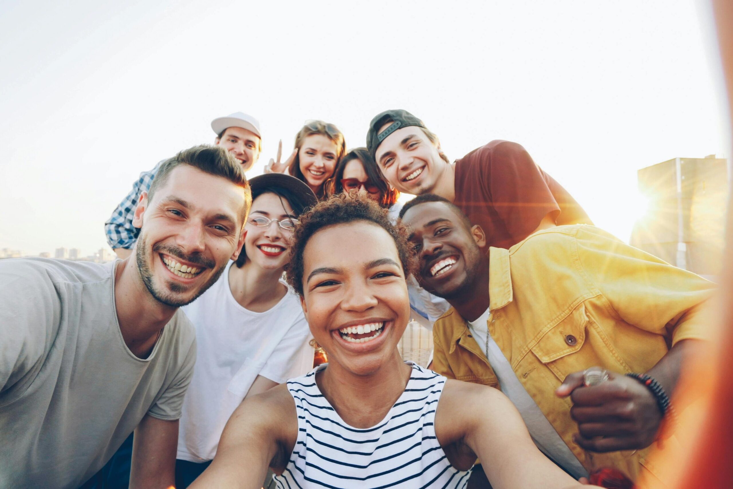 A diverse group of friends taking a joyful selfie outdoors during sunset.