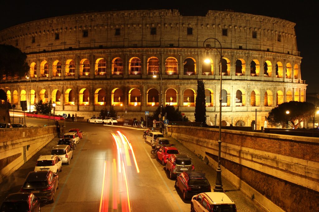 A captivating night view of the iconic Colosseum in Rome, beautifully illuminated and surrounded by city life.