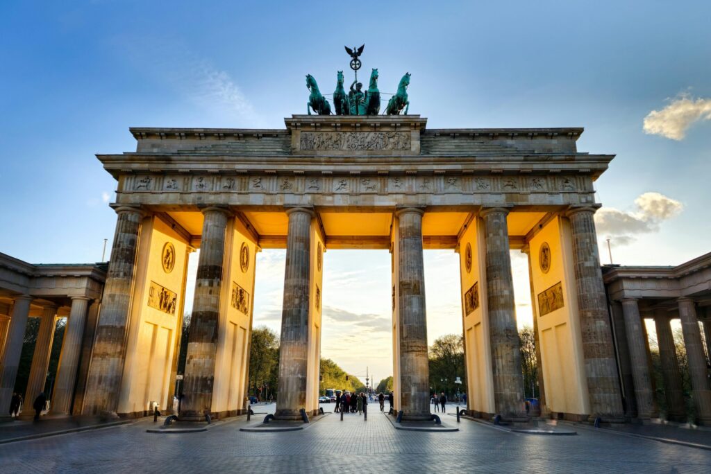 The iconic Brandenburg Gate in Berlin, captured during sunset with glowing light.